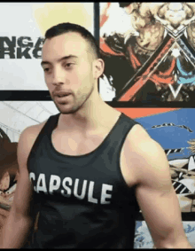 a man is wearing a black tank top that says capsule