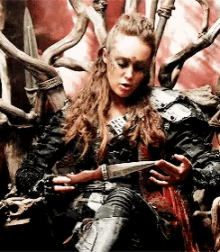 a woman is sitting on a throne holding a knife in her hands .