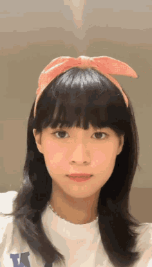 a girl wearing a white shirt with the letter k on it looks at the camera