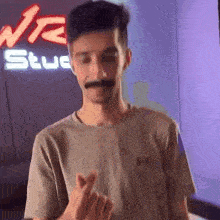 a young man with a mustache is making a heart shape with his fingers .