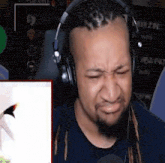 a man with dreadlocks wearing headphones is making a funny face .