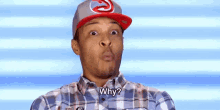 a man wearing a baseball cap and a plaid shirt is making a funny face and asking why .