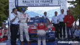 a group of people standing in front of a rallye de france sign