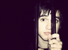 a young man behind bars with a finger pointing at him