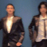 a couple of people standing next to each other wearing suits and ties