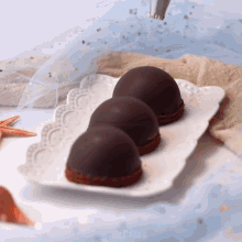 three chocolate covered desserts on a white plate with the word cakes on the bottom
