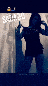 a woman taking a selfie in front of a wall that says sabado on it