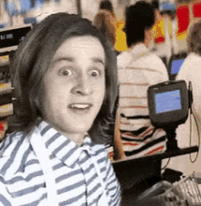 a young man in a striped shirt is sitting at a counter in front of a screen that says ' lc one '
