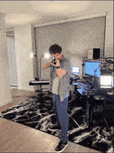 a man is holding a gun in a room with a keyboard and a monitor