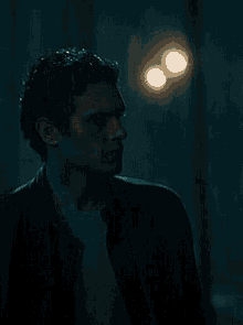 a man in a black jacket is standing in a dark room .