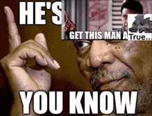 a man is pointing at a sign that says he 's get this man a true ... you know