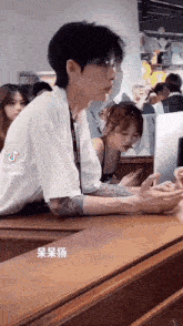 a man with a tattoo on his arm is sitting at a table with a woman looking at his phone .