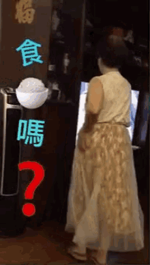 a woman in a long skirt is standing in front of a television and a bowl of rice .