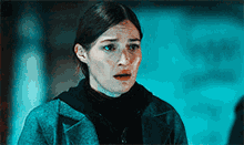a woman is making a funny face in a dark room with a blue light behind her .