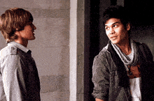 two young men are standing next to each other and one of them has a scarf around his neck