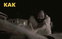 a man with a beard is standing next to a car with a hammer in his hand .