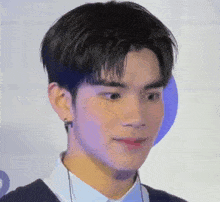 a close up of a young man 's face wearing earring and a shirt .