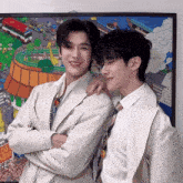 two men are posing for a picture in front of a colorful painting