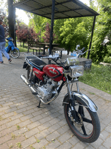 a red motorcycle with a chrome fender is parked on a brick pavement