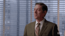 a man in a suit and tie is looking out of a window .
