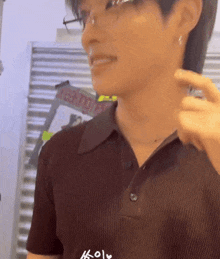 a man wearing glasses and a brown shirt is standing in front of a ladder that says reading