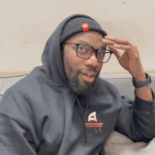 a man wearing glasses and a hoodie with the letter a on the front