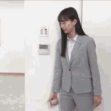 a woman in a suit is standing next to a wall holding a toy