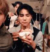a man is eating a hamburger with chopsticks while another man looks on .
