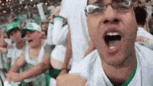 a man wearing glasses and a white shirt is screaming in front of a crowd