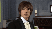 a man in a tuxedo stands in front of a candle in a church