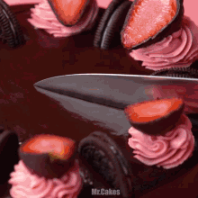 a cake with strawberries and pink frosting is being sliced