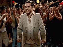 a man in a suit and tie stands in front of a crowd of people