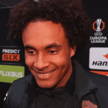 a man is smiling in front of a europa league advertisement
