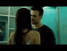 a man and a woman are kissing in front of a mirror in a bathroom .