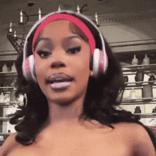 a woman wearing pink headphones and a pink headband looks at the camera