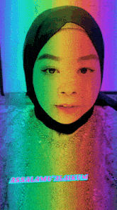 a woman wearing a rainbow colored hijab with the words assalamualaikum on the bottom right