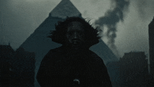 a silhouette of a person in front of a pyramid in the dark