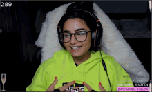 a woman wearing headphones and a neon green hoodie with the number 289 on the bottom