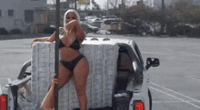 a woman in a bikini is standing on a pole in the back of a truck
