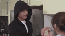 a man in a black hoodie is standing next to a woman