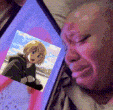 a man is crying while looking at a picture of a anime character on a tablet .