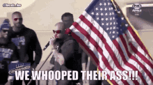 a man holding an american flag says " we whooped their ass !!! "