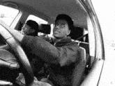 a man wearing glasses is driving a car with another man in the back seat