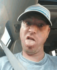 a man wearing a hat is sticking his tongue out while sitting in a car