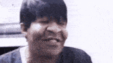 a man with short black hair is making a funny face while looking at the camera .