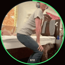 a woman is squatting on a bed with the time of 0:12