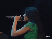 a woman singing into a microphone with rbd.gif written below her