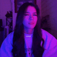 a woman is sitting in front of a purple light and making a face .