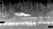 a black and white image of a plane flying over a forest .