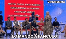 a group of people are sitting in front of a large red sign that says viperissima